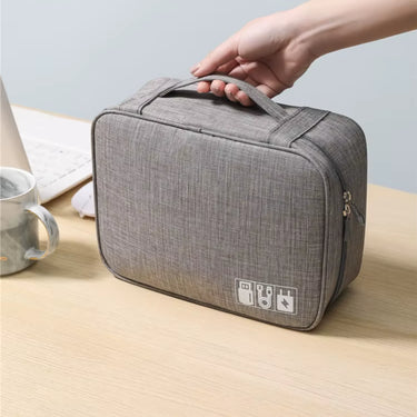 Pochette organisateur gris clair avec 1 compartiment, idéale pour ranger cùbles, chargeurs et accessoires de voyage. Compacte et pratique avec poignée.